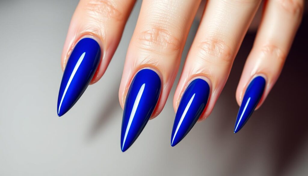 A close-up, high-definition photograph of a set of elegant, royal blue stiletto nails, with a glossy, mirror-like finish that reflects the light beautifully. The nails are long, slender, and tapered to a sharp point, exuding a sense of glamour and sophistication. The lighting is soft and diffused, creating gentle shadows that accentuate the curves and contours of the nails. The background is a neutral, muted tone, allowing the vibrant blue hue of the nails to take center stage and command attention. The overall mood is one of refined luxury and captivating allure.